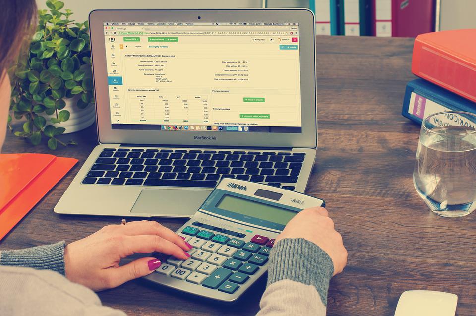 bookkeeping-tax digital (1) (002) Person using calculator with laptop displaying financial software and invoices
